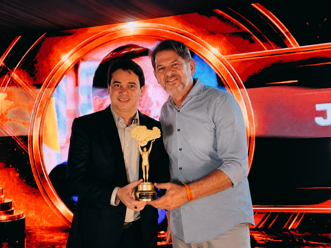 Junior Mano recebendo o Prêmio Sertão de Ouro em Crateús ao lado de homenageado durante cerimônia de premiação